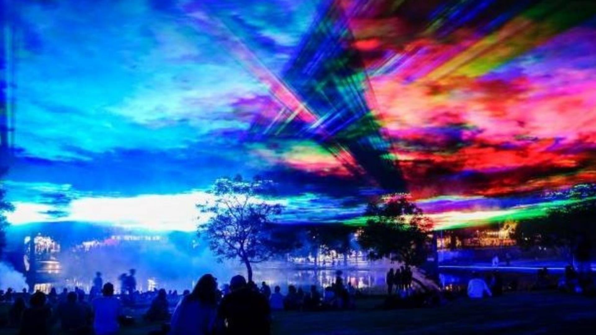 Hazing lights and lasers shine across a landscape at night, mimicking the Northern Lights. Borealis by Dan Acher in Greenwich and Woolwich.