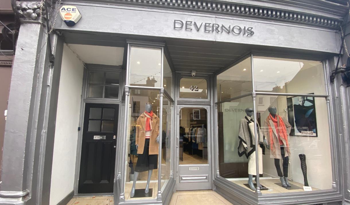 Outside Devernois in Blackheath. A silver shop front with three mannequins in the window wearing clothing items.