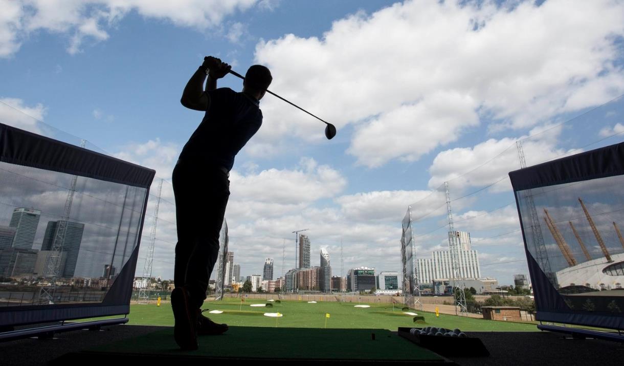 A golfer hits a golf ball at Greenwich Peninsula Golf Driving Range.