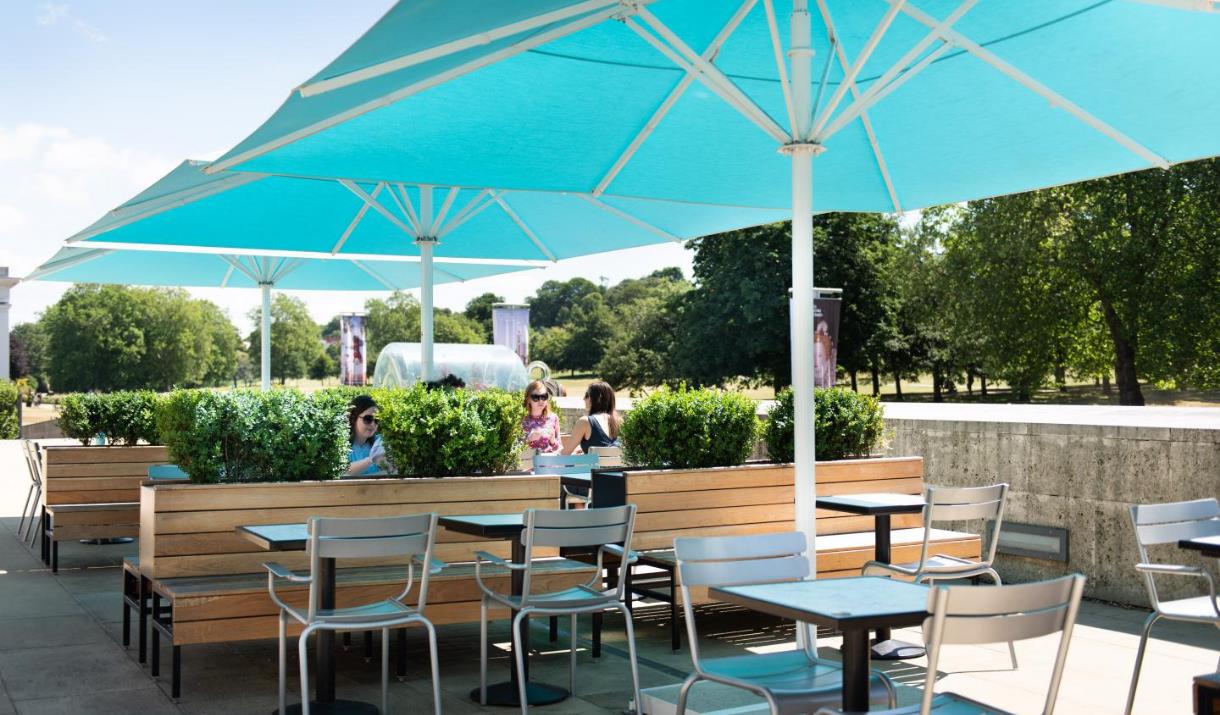 Outside seating at the Parkside Café showing multiple seating areas, benches and the option for big umbrellas