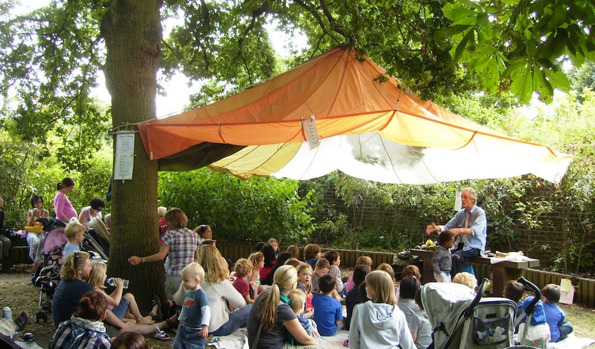 Storyteller and group of families under an oak tree