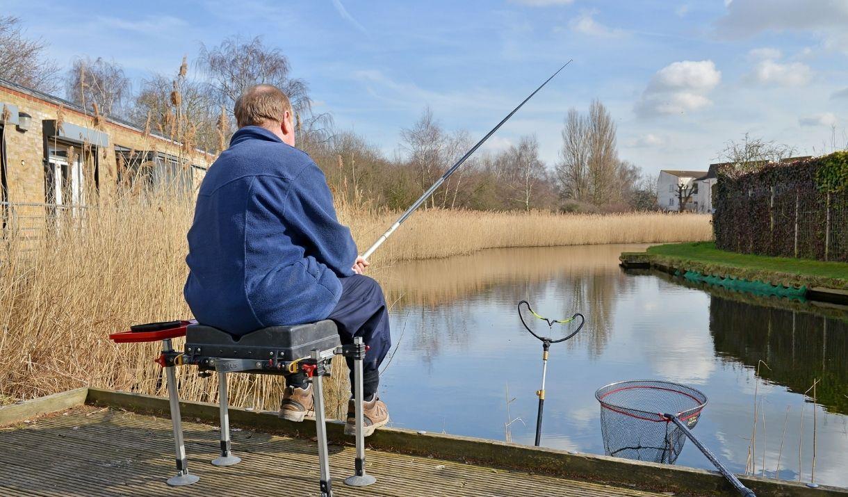 A person fishing by the lake at Tump 53 in Thamesmead