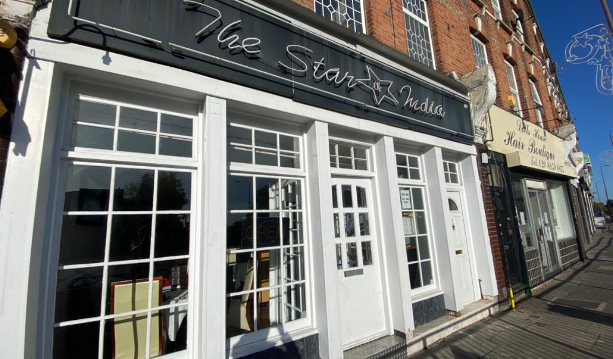 Outside The Star of India, presenting a bright white building with a black banner and multiple windows.