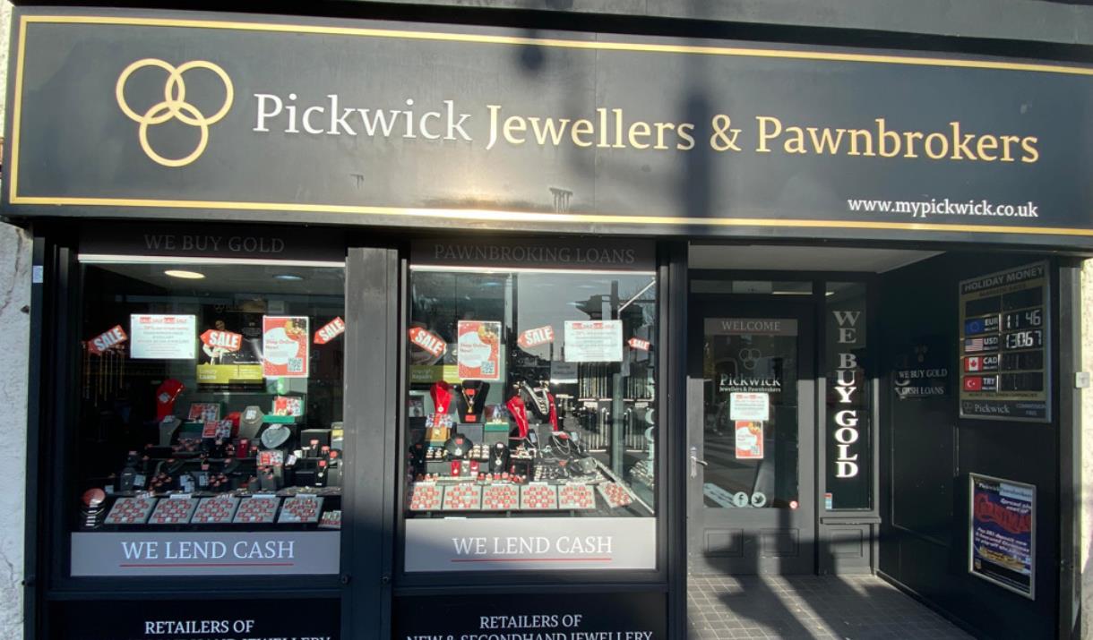 Outside Pickwick Jewellers & Pawnbrokers in Eltham. A black and gold designed shop with a selection of jewellery in the window.