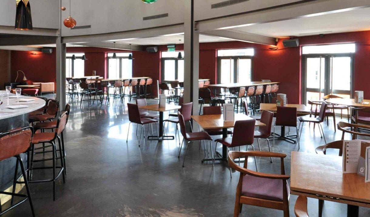 Interior image of Zerodegrees Microbrewery Restaurant with a bar and high chairs on the left side and more seating on the other side.