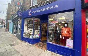 Outside Cancer Research UK, Blackheath. A blue shop filled with a range of different products.