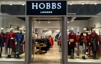 Outside Hobbs at The O2. A modern shop with multiple windows that show a huge selection of clothing and accessories.