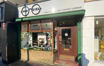 Outside For Eyes Opticians in Greenwich. A small and charming shop with a green and white design and a front window filled with glasses.