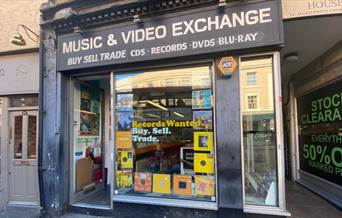 Outside Music & Video Exchange in Greenwich. A black and white shopfront with a huge selection of items inside.