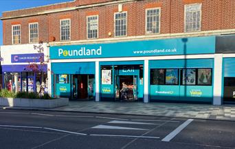 Outside Poundland in Eltham. The picture shows a large turquoise building with a wide range of products.