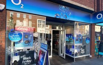 Outside O2 in Eltham. This picture shows a modern shop with lots of blue O2 advertising and windows looking onto a range of products.