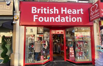 Outside British Heart Foundation in Eltham. The picture shows a red and white shop front with a wide selection of items inside.