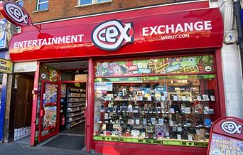 Outside CeX in Eltham. Showing a red and white shop with a selection of electronics presented through the window.