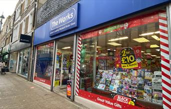 Outside The Works in Woolwich. Showing a blue and white shop front with a range of exciting products inside waiting to be found.