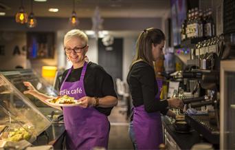 Two ladies working at Artfix cafe serving food and making drinks.