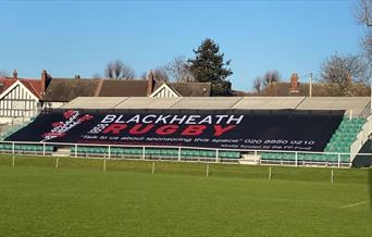 Blackheath Rugby Club ground with green seating in the background and black banner with the stadium name over the seating.