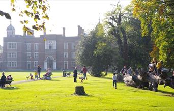 Kids playing beside Charlton House in Charlton Park and Parents relaxing on benches on a beautiful Sunny Day