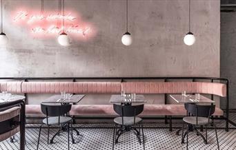 Interior image of Greenwich Grind branch with modern contemporary setting with natural light, pink seating and black and white tiled floor.