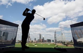 A golfer hits a golf ball at Greenwich Peninsula Golf Driving Range.