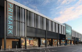 A picture taken outside of Primark in Charlton, showing a very large building with windows revealing a selection of products.