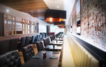 Inside Rixos Bar and Grill, a stylish room with brick styled walls, a wooden floor and leather seats.