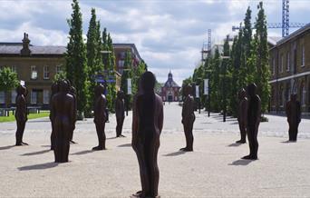 A view along No.1 Street within Royal Arsenal, Woolwich, featuring the famous "Assembly" statues by Peter Burke