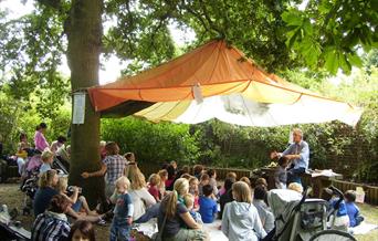 Storyteller and group of families under an oak tree