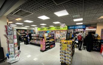 Inside WHSmiths in Greenwich, showing a small newsagents filled with snacks, drinks, cards, magazines, books and more.