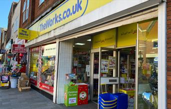 Outside The Works Eltham. showing a blue and yellow themed shop front.