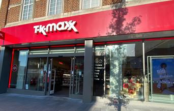 Outside Tk Maxx Eltham, a red and white building with multiple windows showing a stunning inside area.