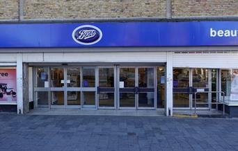 Outside Boots in Eltham, showing a blue and white styled shop with a glass door entrance.