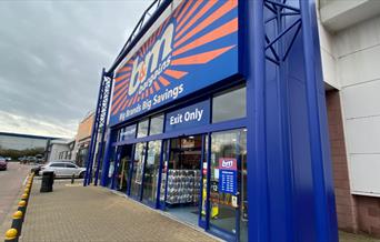 Outside B&M in Charlton. A large blue and orange building with automatic doors, located next to a car park.