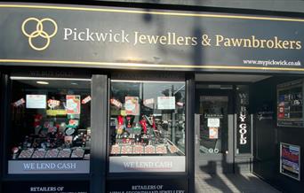 Outside Pickwick Jewellers & Pawnbrokers in Eltham. A black and gold designed shop with a selection of jewellery in the window.