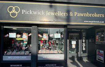Outside Pickwick Jewellers & Pawnbrokers in Eltham. A black and gold designed shop with a selection of jewellery in the window.