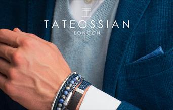 Tateossian London. A man wearing a blue blazer and blue bracelets. A white logo saying Tateossian London sits at the top of the image.