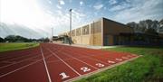 A photo taken of Sutcliffe Park Sport Centre's running track, showing a red track surrounded by fields and a building.