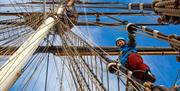 Woman climbs the the rigging at the Cutty Sark Rig Climb