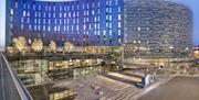 Main view of the Aloft London Excel exterior with deep blue and purple shades during evening time