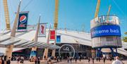 The O2 dome in white covering with 5 yellow stands visible and large glass door entrance