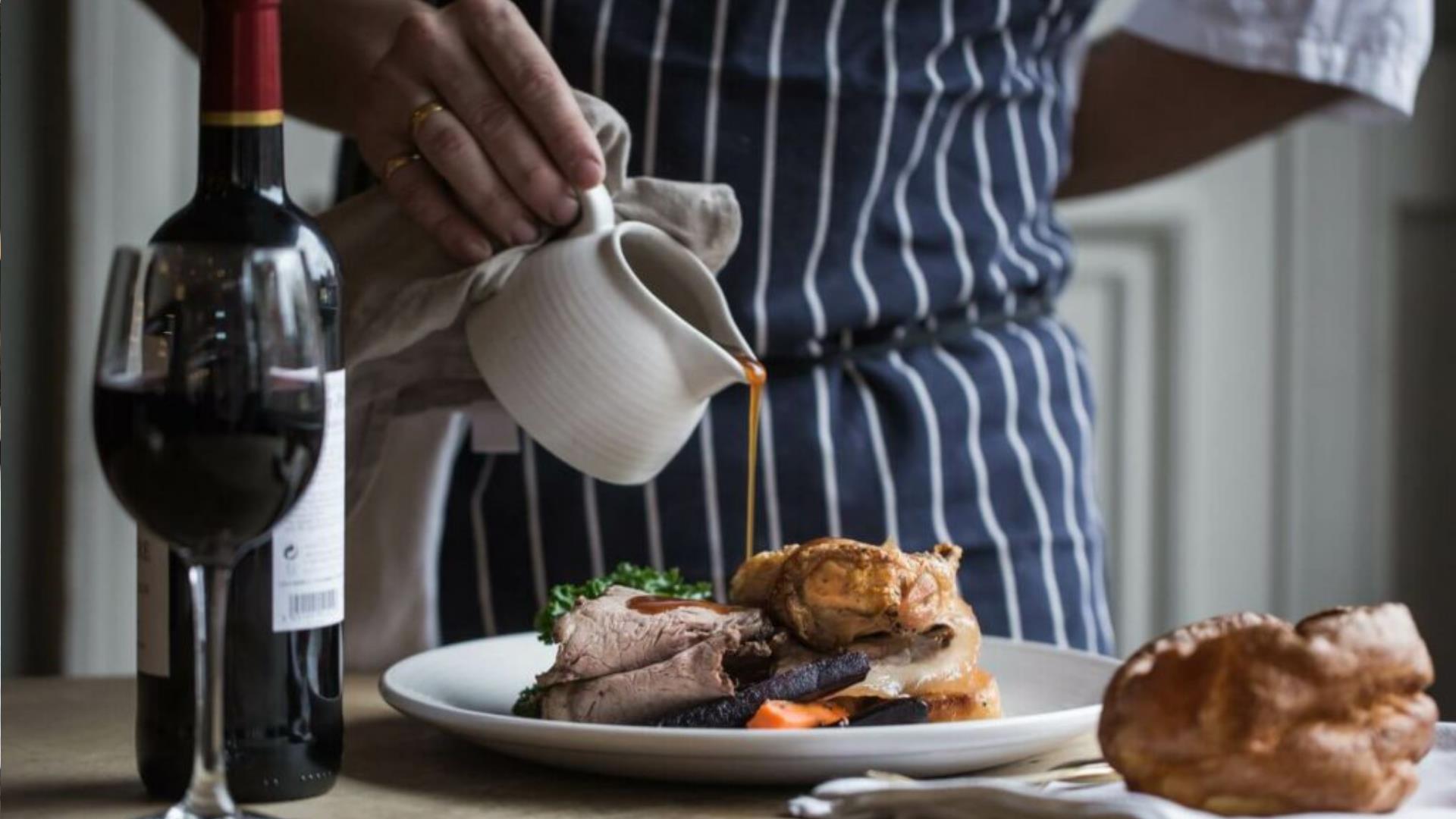 A chef pours gravy over a delicious Sunday roast.