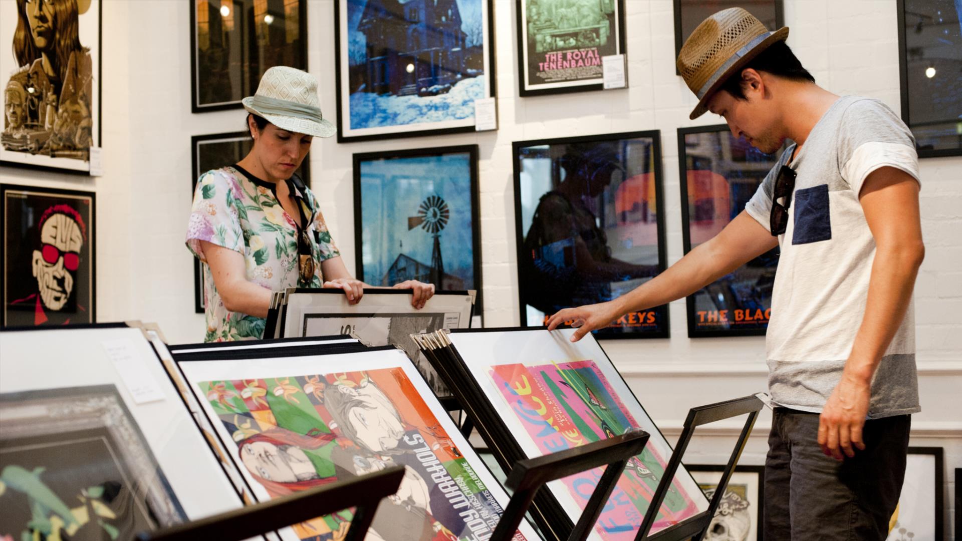 Two people look through prints at a gallery in Greenwich.