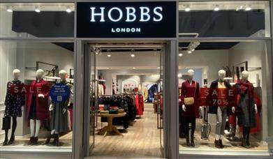 Outside Hobbs at The O2. A modern shop with multiple windows that show a huge selection of clothing and accessories.