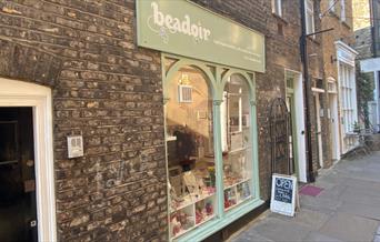 Outside Beadoir in Greenwich. This picture shows a welcoming shop painted mint green and a lovely indoor area.