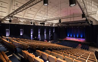 Blackheath Halls, a beautifully designed Hall with a white curved ceiling, multiple rows of  chairs onlooking the stage.