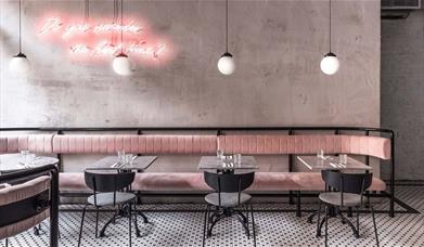Interior image of Greenwich Grind branch with modern contemporary setting with natural light, pink seating and black and white tiled floor.