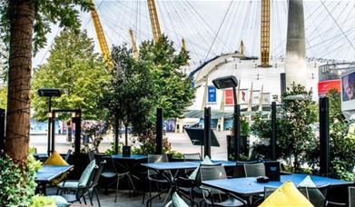 Outside seating at Greenwich Kitchen Bar & Grill in a modern and intimate setting looking out onto a vibrant Balearic themed terrace and The O2 arena.