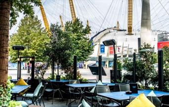 Outside seating at Greenwich Kitchen Bar & Grill in a modern and intimate setting looking out onto a vibrant Balearic themed terrace and The O2 arena.