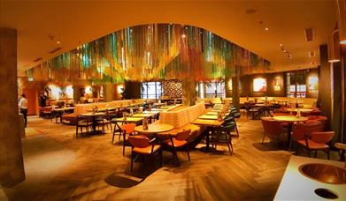 Inside Nando's at The 02, showing a large open area with lots of seating, wooden floors and a unique Portuguese designed room.