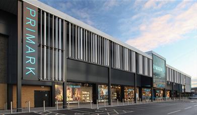 A picture taken outside of Primark in Charlton, showing a very large building with windows revealing a selection of products.