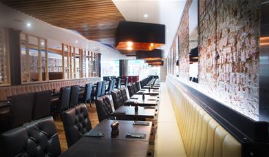 Inside Rixos Bar and Grill, a stylish room with brick styled walls, a wooden floor and leather seats.